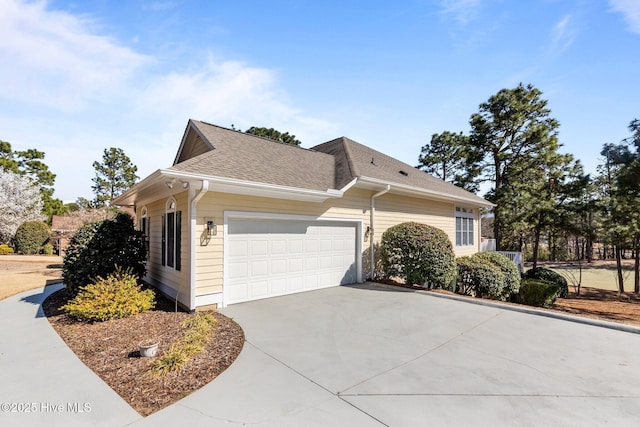 view of home's exterior featuring concrete driveway, an attached garage, and roof with shingles