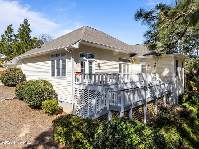 rear view of property with crawl space, a wooden deck, and a shingled roof