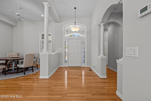 entrance foyer featuring decorative columns, baseboards, light wood-style floors, and ceiling fan