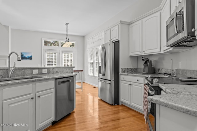 kitchen with a sink, light wood-style floors, appliances with stainless steel finishes, and white cabinetry