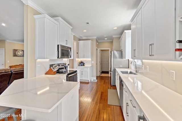 kitchen featuring stainless steel appliances, white cabinets, visible vents, and a sink