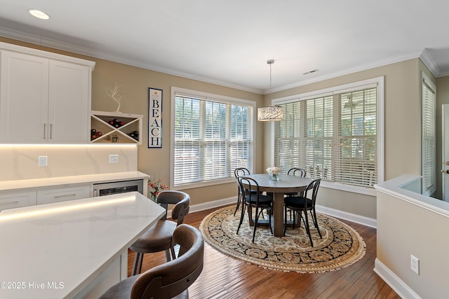 dining room featuring baseboards, visible vents, dark wood-style floors, ornamental molding, and a bar