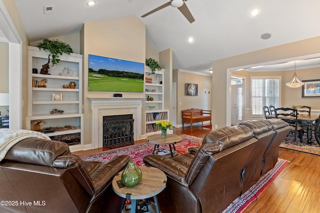 living room with ceiling fan, lofted ceiling, crown molding, a high end fireplace, and wood finished floors
