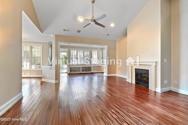 4155 Windham Ln, Southport, NC 28461 - unfurnished living room with lofted ceiling, radiator heating unit, ceiling fan, a fireplace, and dark wood finished floors