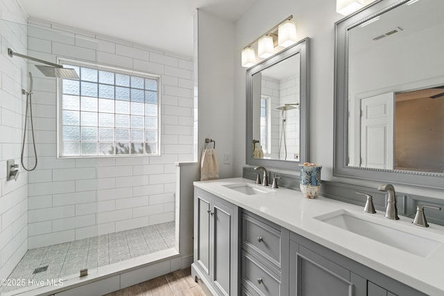 full bathroom with visible vents, tiled shower, and a sink