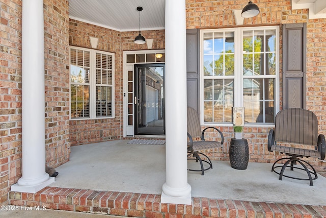 view of exterior entry with a porch and brick siding