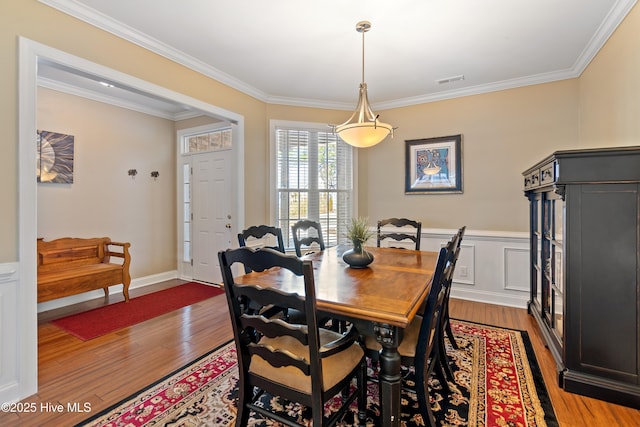 dining area featuring ornamental molding, visible vents, wainscoting, and wood finished floors
