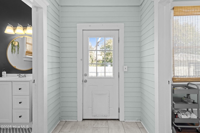 doorway featuring sink and wood walls