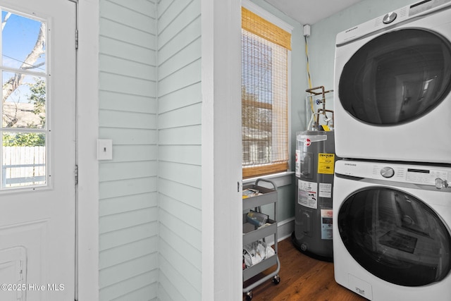 clothes washing area featuring electric water heater, dark hardwood / wood-style floors, and stacked washer / drying machine