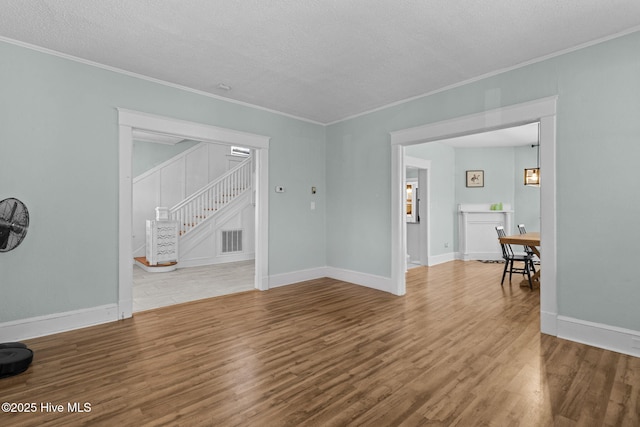 interior space with a textured ceiling, hardwood / wood-style flooring, and crown molding