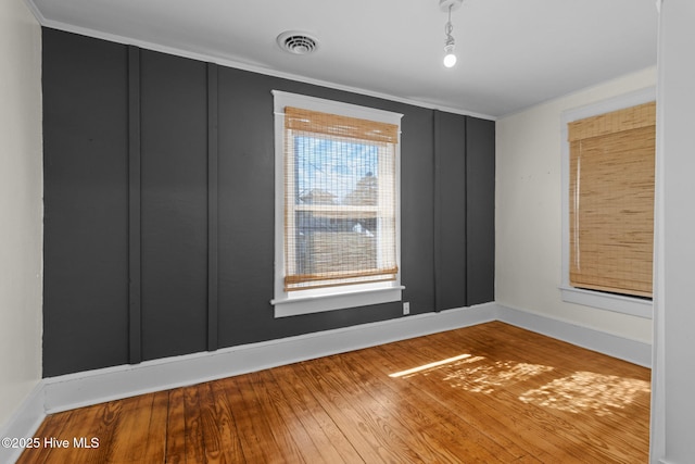 empty room with hardwood / wood-style flooring and crown molding