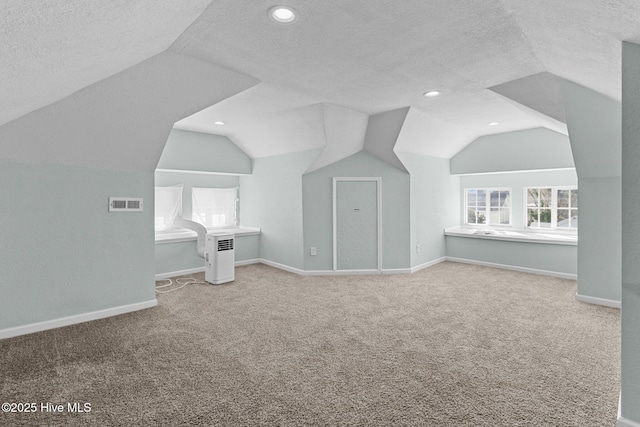 additional living space with lofted ceiling, carpet floors, and a textured ceiling