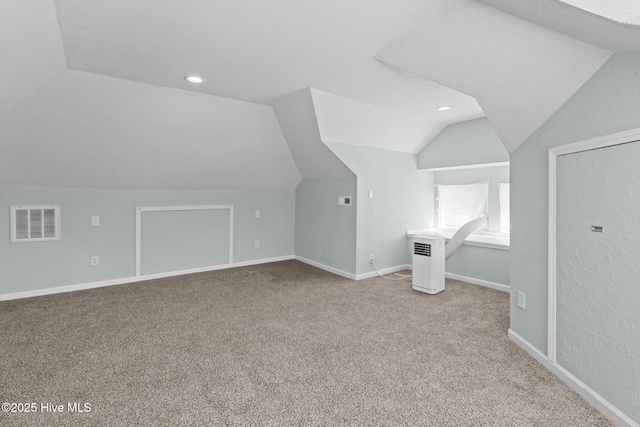 bonus room featuring a textured ceiling, vaulted ceiling, and light colored carpet