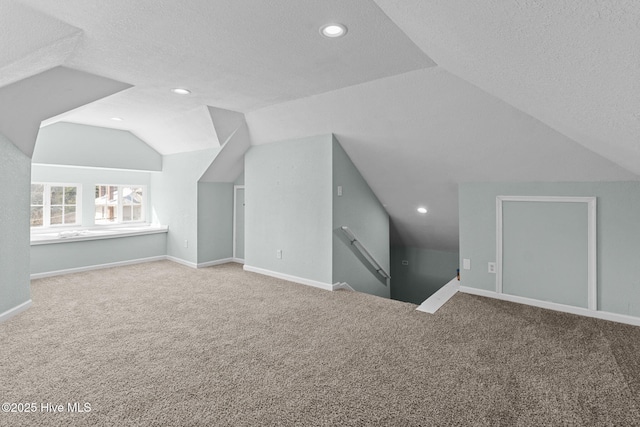 additional living space featuring a textured ceiling, vaulted ceiling, and carpet flooring