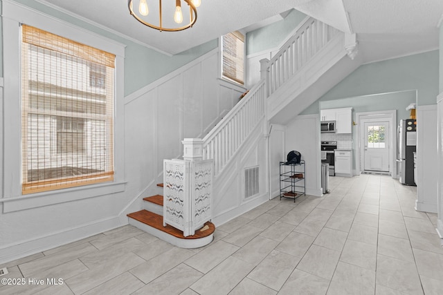 stairway with a chandelier, crown molding, and tile patterned flooring