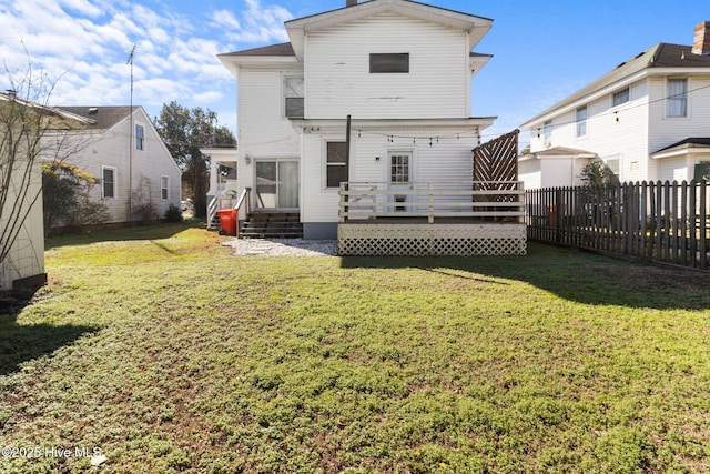 rear view of property with a wooden deck and a lawn