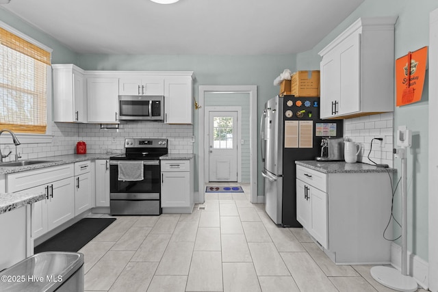 kitchen featuring white cabinets, appliances with stainless steel finishes, sink, and light stone countertops