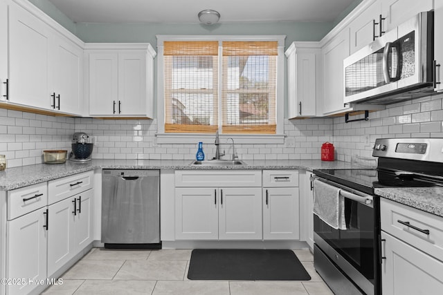 kitchen featuring appliances with stainless steel finishes, light stone countertops, decorative backsplash, sink, and white cabinetry