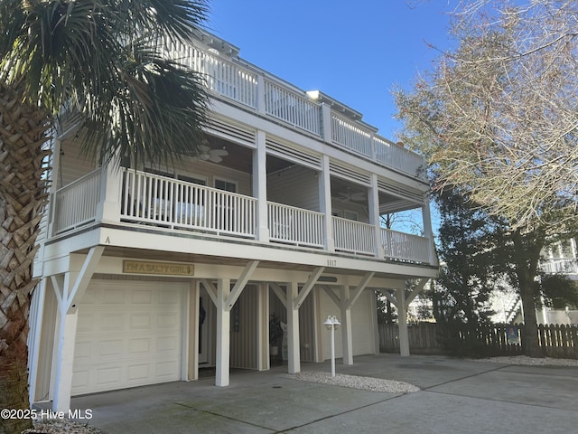 view of front of property featuring a ceiling fan, concrete driveway, a balcony, an attached garage, and fence