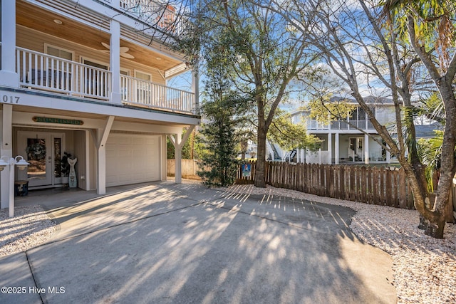 view of home's exterior with driveway, a balcony, a garage, and fence