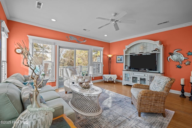 living room with visible vents, crown molding, and wood finished floors