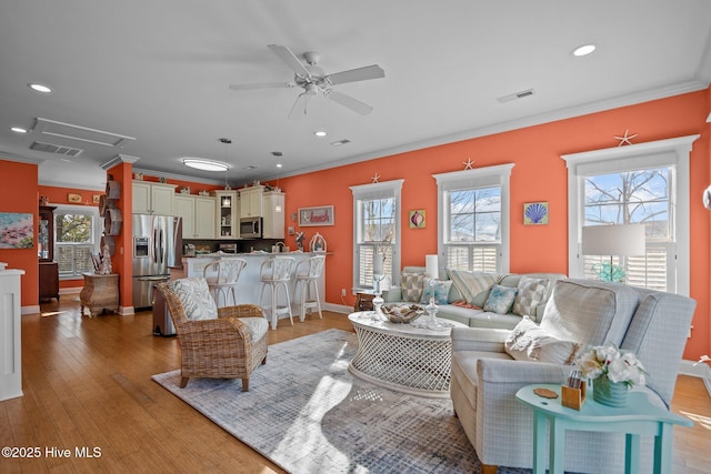 living room featuring hardwood / wood-style flooring, recessed lighting, visible vents, a ceiling fan, and ornamental molding