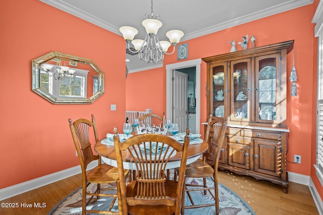 dining room with a chandelier, baseboards, light wood-style flooring, and crown molding