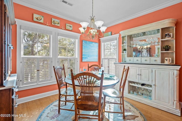 dining space featuring ornamental molding, visible vents, a notable chandelier, and light wood-style flooring