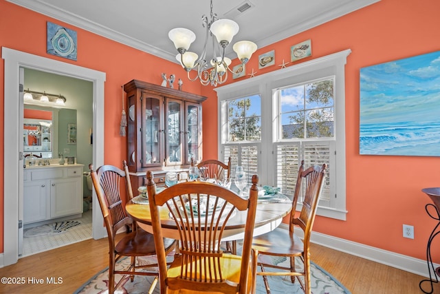 dining room featuring a notable chandelier, visible vents, baseboards, ornamental molding, and light wood-type flooring