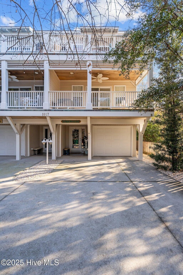 coastal inspired home featuring concrete driveway, a balcony, and an attached garage