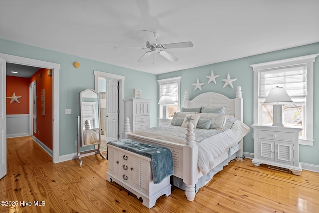 bedroom featuring a ceiling fan, wainscoting, and light wood-style flooring