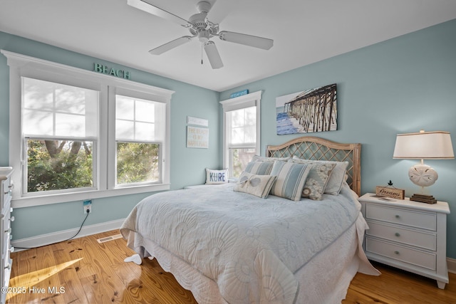 bedroom featuring a ceiling fan, visible vents, baseboards, and wood finished floors