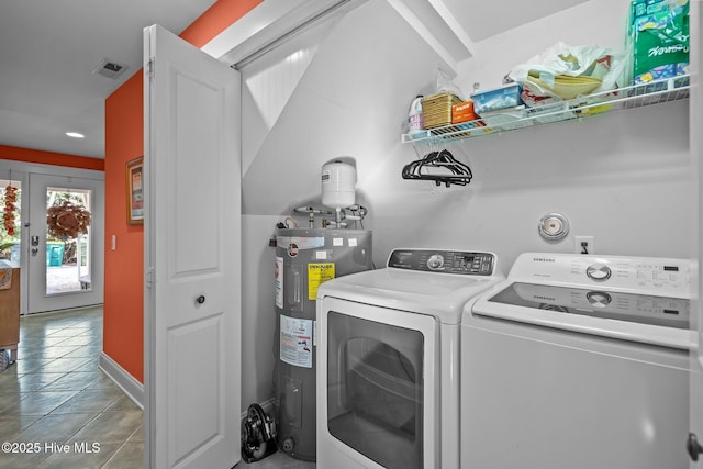 clothes washing area with laundry area, visible vents, electric water heater, tile patterned flooring, and washing machine and dryer