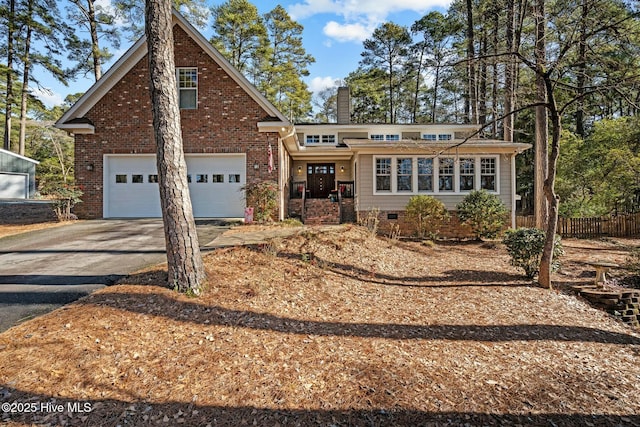 view of front of home featuring a garage, aphalt driveway, a chimney, and brick siding