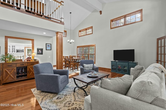 living room featuring beam ceiling, decorative columns, wood finished floors, high vaulted ceiling, and baseboards