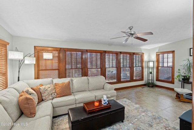 living area featuring ceiling fan, baseboards, and light tile patterned flooring