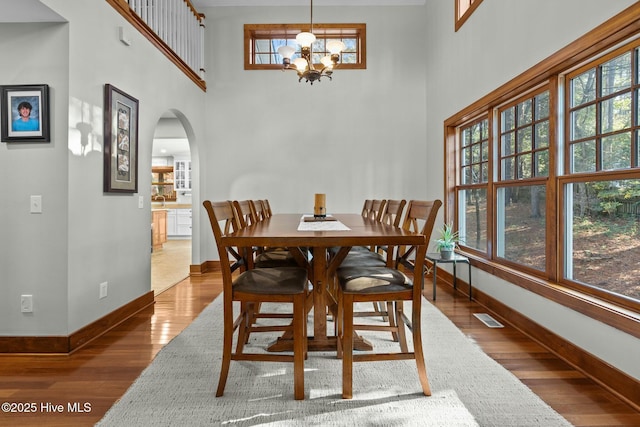 dining space featuring arched walkways, plenty of natural light, and wood finished floors