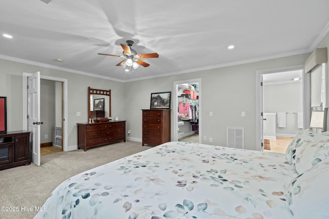 bedroom with a spacious closet, visible vents, crown molding, and light colored carpet