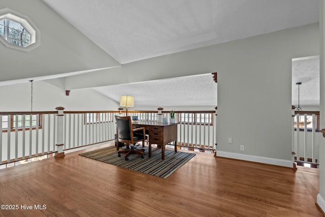 living area with a healthy amount of sunlight, vaulted ceiling, baseboards, and wood finished floors