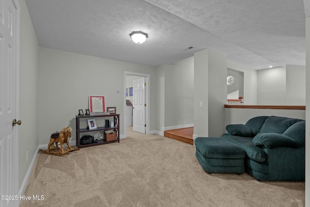 living area with light carpet, a textured ceiling, and baseboards