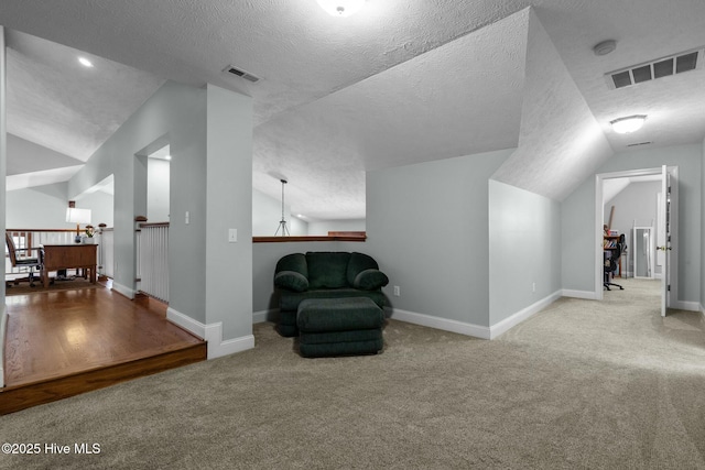 sitting room with baseboards, visible vents, light colored carpet, lofted ceiling, and an upstairs landing