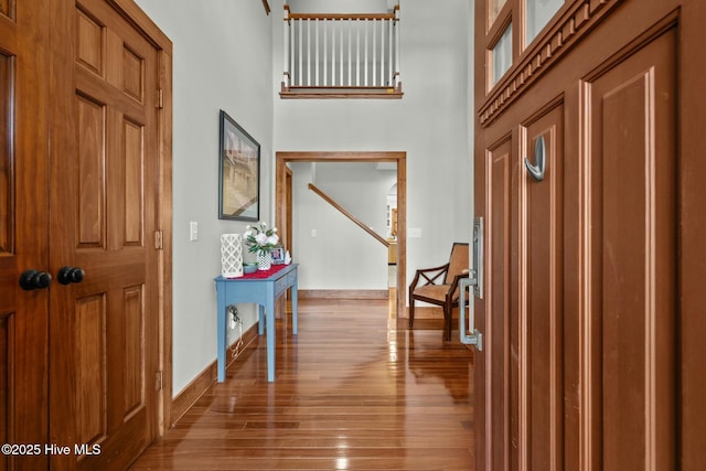 entrance foyer with a towering ceiling, light wood-style floors, and baseboards