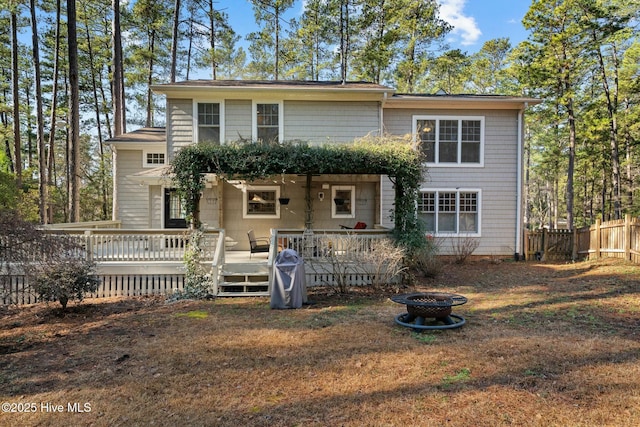 rear view of house featuring a deck, fence, and a fire pit