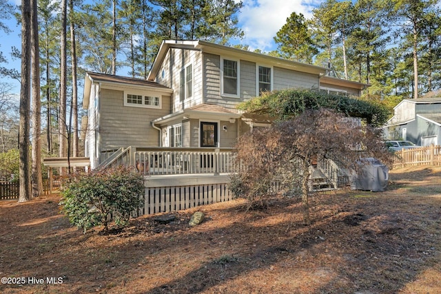 rear view of house with fence and a deck