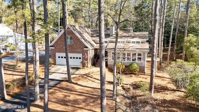 view of front of house featuring driveway, a garage, and brick siding