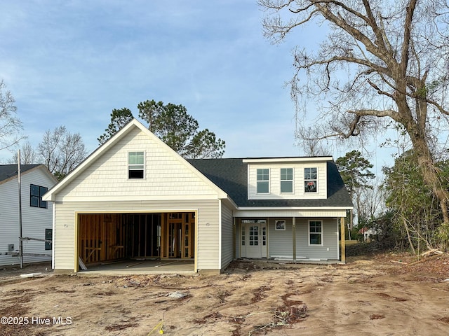 view of front of home with an attached garage, covered porch, and a shingled roof