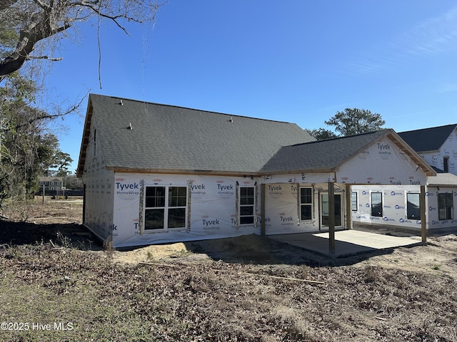 back of house featuring roof with shingles and a patio area