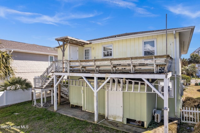 rear view of property featuring board and batten siding, fence, a wooden deck, and stairs