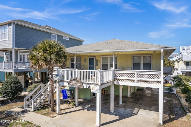 view of front of property featuring a porch, a shingled roof, concrete driveway, stairway, and a carport