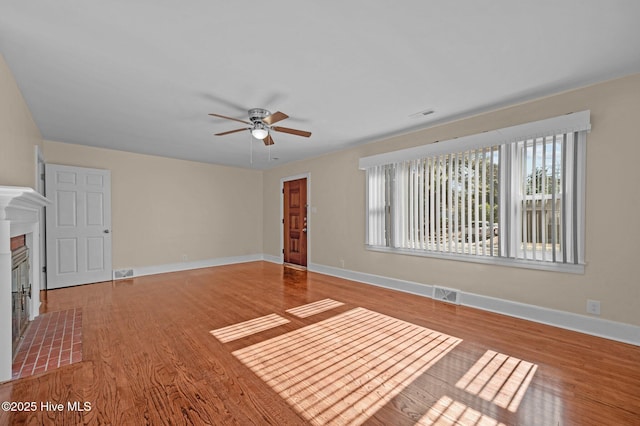 unfurnished living room featuring a tiled fireplace, hardwood / wood-style floors, and ceiling fan